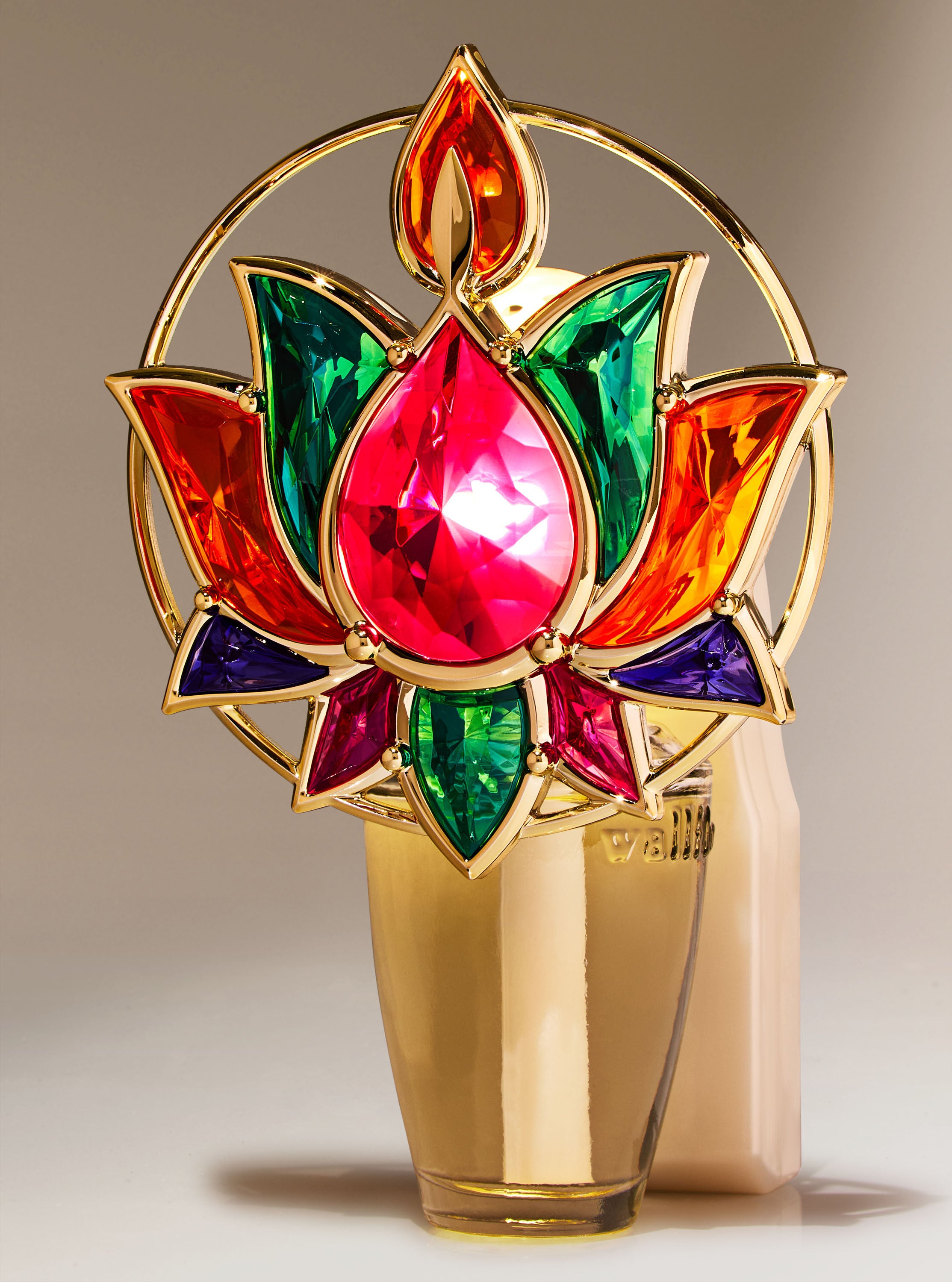 A gold fragrance plug with a lotus flower made of colorful gems