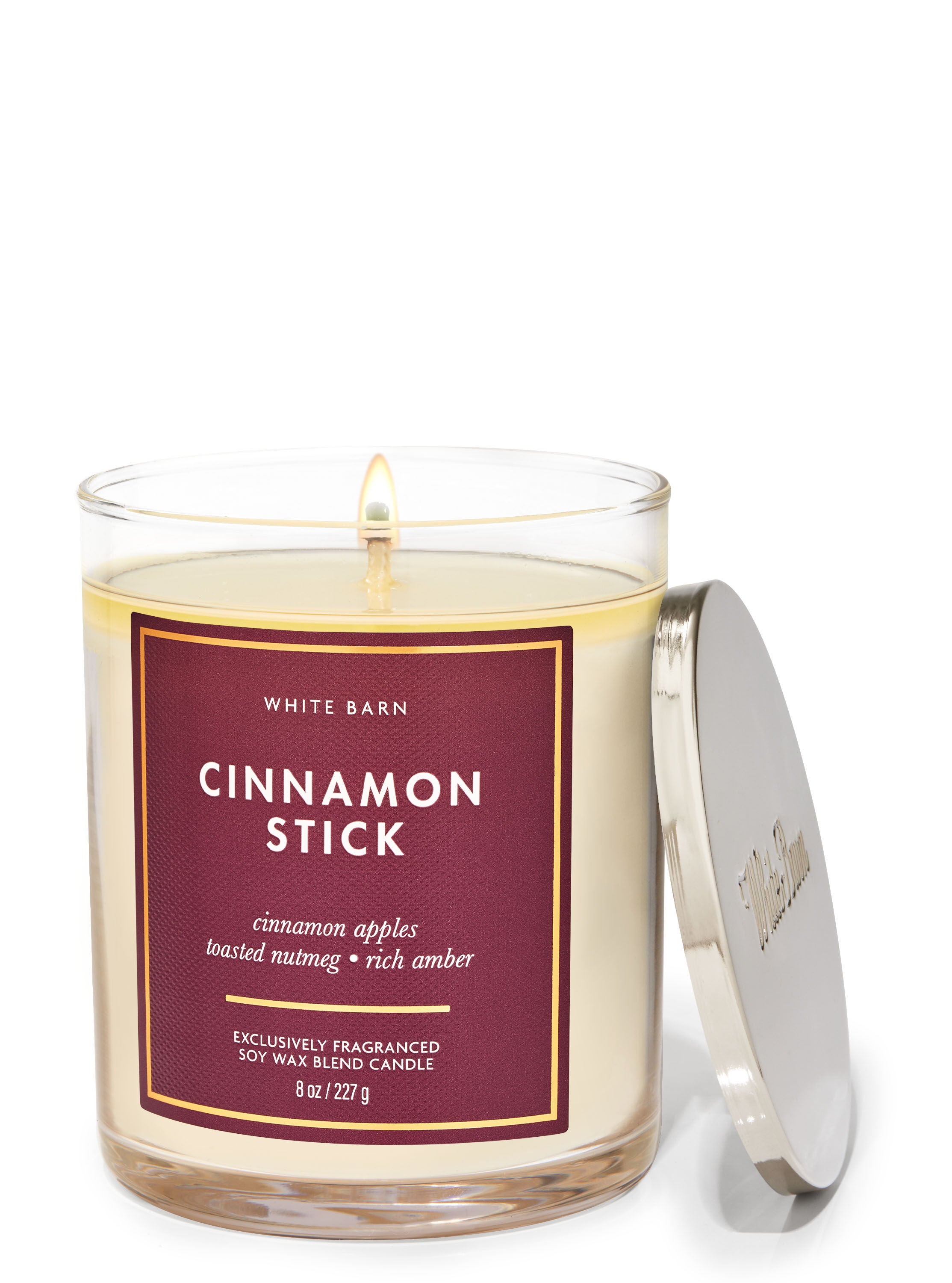 A glass jar single wick candle with a red label
